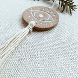 Handcrafted ceramic evil eye ornament with tassel, styled view